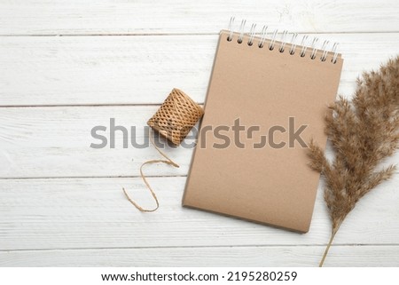 Stylish kraft notebook and decor elements on white wooden table, flat lay. Space for text