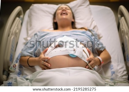 A woman having painful contractions lying in the hospital bed waiting for labor. Royalty-Free Stock Photo #2195285275