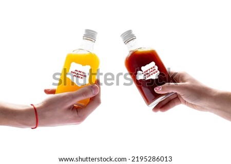 Filter coffee in a glass bottle with a white cap and fresh juice in a glass bottle are held by two hands on a white background