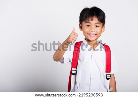 Asian adorable toddler smiling happy wearing student thai uniform red pants show thumb up finger in studio shot isolated on white background, Portrait little children boy preschool, Kid Back to school