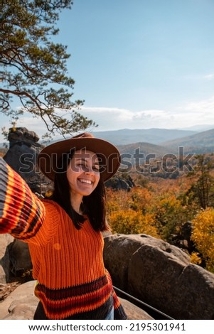 happy smiling woman taking selfie picture on the top of the mountain autumn forest on background