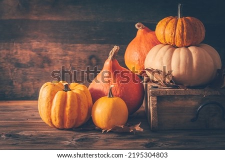 Rustic autumn still life with pumpkins and golden leaves on a wooden surface