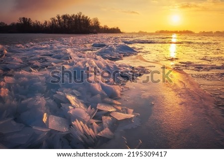 Winter landscape with sunset fiery sky and frozen icy sea coast. Daybreak