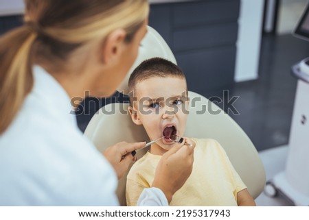 Dentist doing regular dental check-up to little boy. Boy having his teeth examined by a dentist. Cute boy smiling while teeth exam . Happy boy sitting in dentists chair and having check up teeth