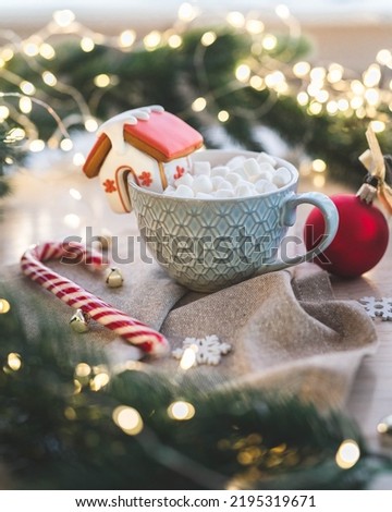 holiday cup of cocoa with a house of cookies on the background of garlands