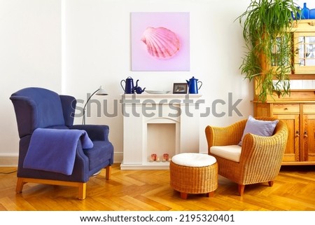 Custom-made home decoration concept: living room with a wing and a wicker chair, and a square canvas print of a pink shell picture.