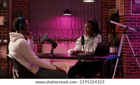 African american woman content creator recording podcast with singer celebrity in home studio. Online radio host talking in interview with influencer for entertainment internet show late at night.