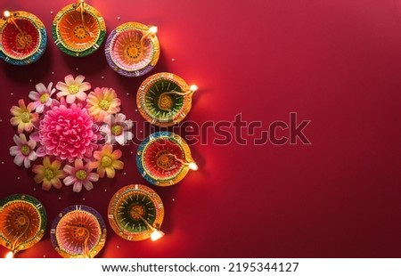 Happy Diwali - Clay Diya lamps lit during Diwali, Hindu festival of lights celebration. Colorful traditional oil lamp diya on red background Royalty-Free Stock Photo #2195344127