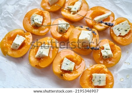 Apricots or peaches baked with blue cheese and lavender sprigs. Delicious dessert with fruits and cheese.Light background, banner, catering menu recipe, place for text. Sweet dessert with fruits