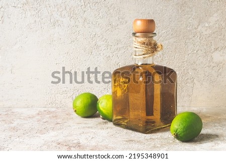 a bottle of tequila and limes on a light table Royalty-Free Stock Photo #2195348901