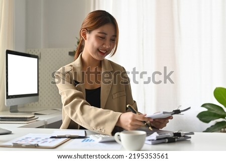 Asian cheerful business woman accountant working audit and calculating expense financial summary report balance sheet statement over white screen computer as a background.