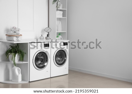 Interior of light laundry room with washing machines and shelving units Royalty-Free Stock Photo #2195359021