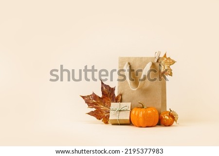Fall Gift or Sale concept. Shopping paper bag, with golden maple leaves and pumpkins. autumn decor. Thanksgiving. Copy space