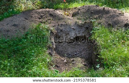 Freshly dug pit in the middle of green grass in meadow Royalty-Free Stock Photo #2195378581