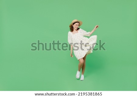 Full size young happy smiling charming cute woman she 20s wears white clothes hat play with fluttering dress isolated on plain pastel light green background studio portrait. People lifestyle concept