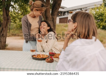 Joyful young caucasian women enjoy spending time outdoors at picnic. Girlfriends wear spring casual clothes. Mood, lifestyle, concept.