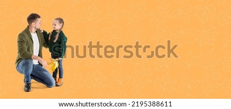 Portrait of happy father and daughter with autumn leaves on orange background with space for text