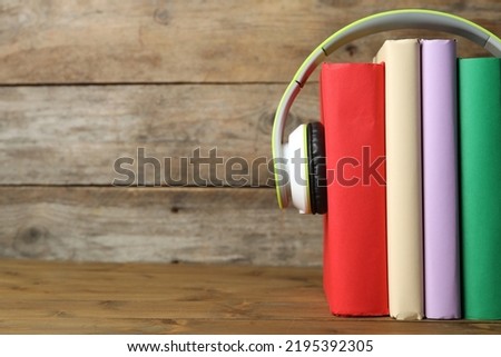 Books and modern headphones on wooden table, closeup. Space for text