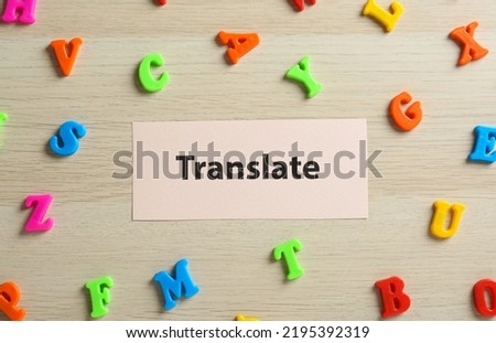 Card with word Translate and plastic letters on wooden table, flat lay
