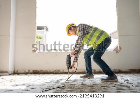 Construction worker Using an electric jackhammer to drill perforator equipment making holes before pouring the floor to be strong at construction site, Concept of worker and residential building. Royalty-Free Stock Photo #2195413291