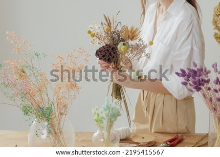 Medium height woman working with dried flowers assemble composition, decor and floristry concept Royalty-Free Stock Photo #2195415567
