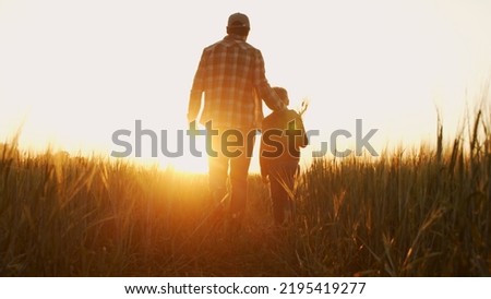 Farmer and his son in front of a sunset agricultural landscape. Man and a boy in a countryside field. Fatherhood, country life, farming and country lifestyle. Royalty-Free Stock Photo #2195419277