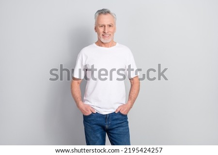 Portrait of attractive cheerful grey haired man holding hands in pockets isolated over grey pastel color background Royalty-Free Stock Photo #2195424257