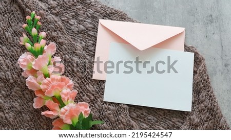 Flat lay shot of white blank card and eco paper envelope on yarn background