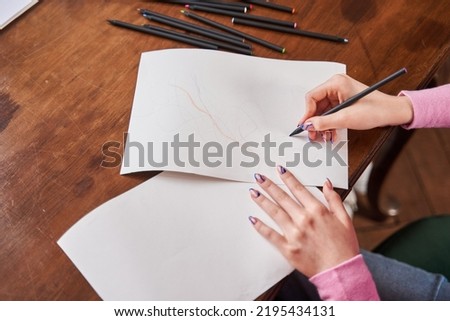Teenager girl drawing at the table during her session at the psychotherapist