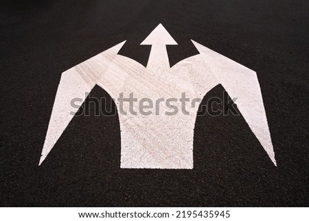 Road arrow sign - three way intersection painted road sign. White pained arrow symbol on dark black sealed bitumen asphalt road surface