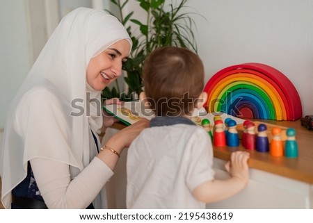 A Musllim teacher and preschool child playing together with colorful toys in the Montessori school classroom or kindergarten. Royalty-Free Stock Photo #2195438619