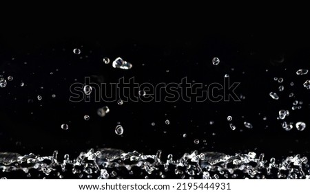 horizontal image. Water splashes in the air. Water waves and airdrops, natural air water movement and black background.