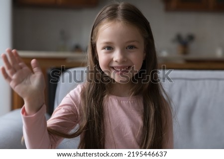 Head shot portrait little girl raise arm makes hello gesture start videocall. Distancing communication to family living abroad, blogging activity, young generation use video call application concept Royalty-Free Stock Photo #2195446637