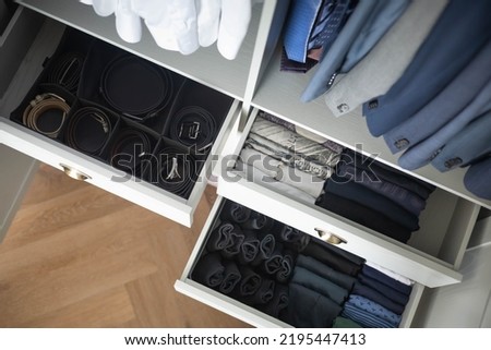 Man cupboard clothes storage organization with open dresser drawer neatly folded belt underwear shirt and socks top view. Male wardrobe hanging clean fashion clothes coat blazer garment attire keeping Royalty-Free Stock Photo #2195447413