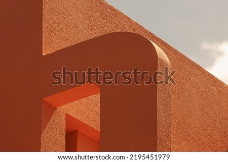 Abstract geometric architecture design. Exterior fragment of modern cement building walls detail, painted orange against a blue sky. volumes, shapes, arches and lines  game. angular. aesthetic 