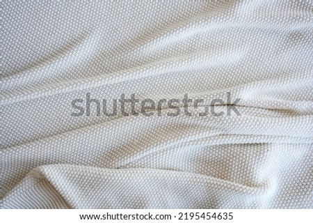 top view of white crumpled knitted blanket. texture background