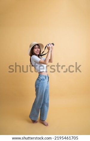 Full length of young attractive Asian woman traveler in casual clothes wearing straw hat taking a photo with retro camera, Tourist girl having cheerful holiday trip concept