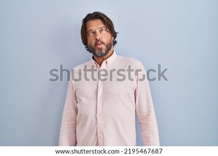 Handsome middle age man wearing elegant shirt background making fish face with lips, crazy and comical gesture. funny expression. 