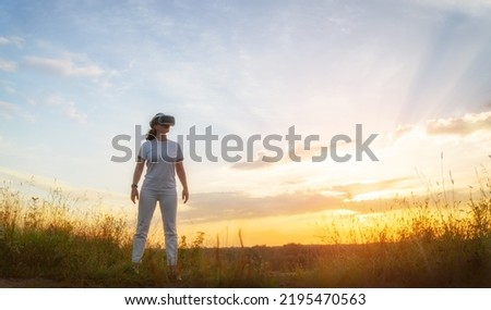 Metaverse technology concept. Woman with VR virtual reality goggles standing on nature. Futuristic lifestyle.