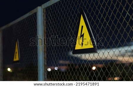 yellow sign high voltage on the fence with mesh