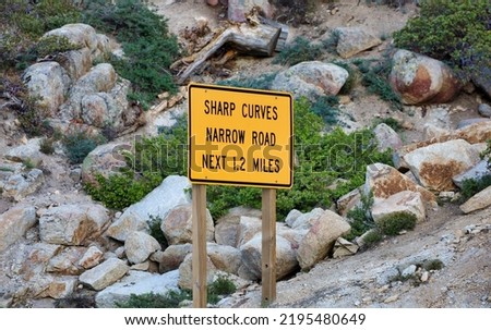 A Sharp Curves Narrow Road Next 1.2 Miles sign on the side of the road.
