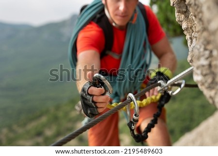 Climber snaps the safety carabiner on the rope. A climber on a cliff ties a safety knot Royalty-Free Stock Photo #2195489603