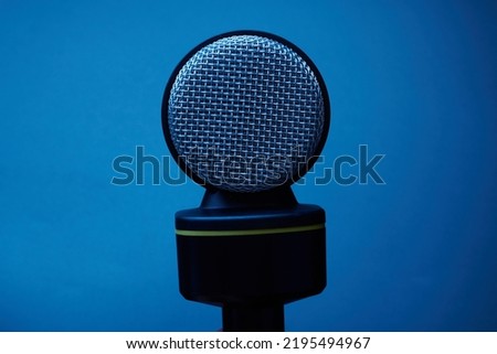 Black microphone isolated on blue background close up