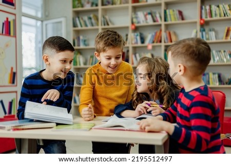 school children in the library reading books, doing homework, prepare a school project for lessons. High quality photo Royalty-Free Stock Photo #2195512497