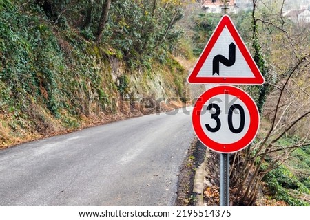 Dangerous turns and speed limit road signs mounted near turning mountain road