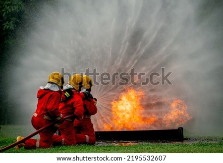 Wide shot of firefighter team with three man support together to distinguish fire using water curtain to control area of fire. Royalty-Free Stock Photo #2195532607