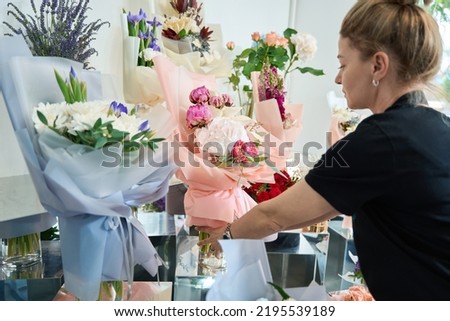 Focused female florist puts matchless bouquet of floral on stand