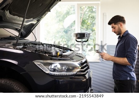 Specialist Inspecting Engine in Order to Find Broken Components. Shot for Animation of Car Service Manager Uses Tablet Computer with Futuristic Augmented Reality Diagnostics Software.