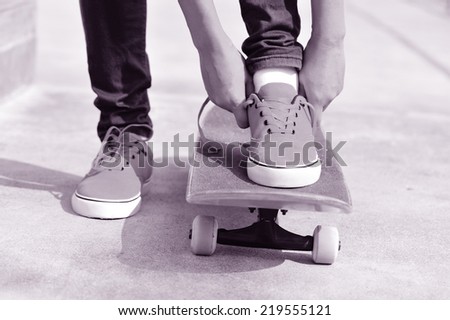 young woman skateboarder tying shoelace 