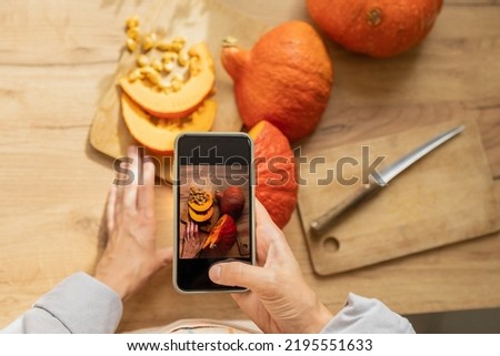 woman takes pictures of orange pumpkins on a cutting board in the kitchen. cooking pumpkin is an eco-friendly food for the whole family. Halloween and All Saints' Day celebrations, autumn holidays